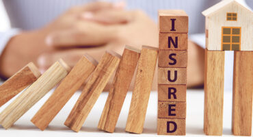 businessman and wooden domino with word insured and home model, insurance concept; Shutterstock ID 705803326; Purchase Order: -